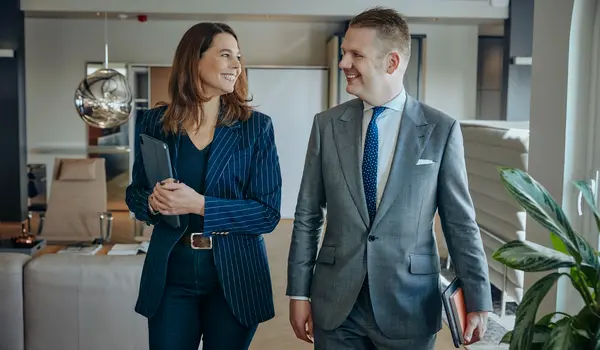 Sybille und Henning walk through the office and smile at each other